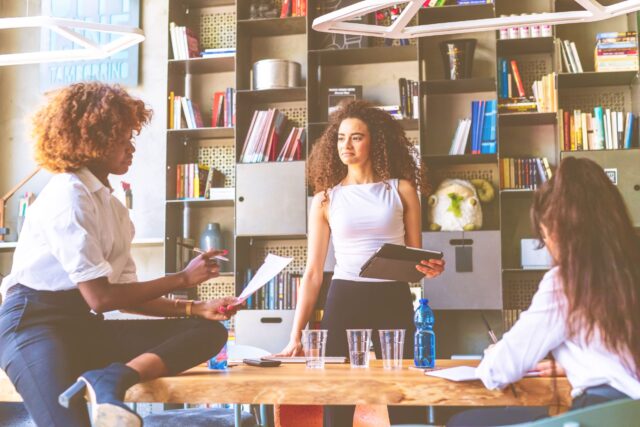 Two young women in the office talk about the steps to empower small businesses in post-COVID recovery.