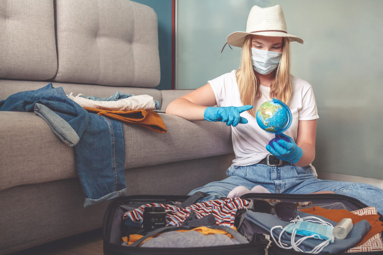 A girl with a face mask looks at the mini globe wondering how the future of tourism will look like.
