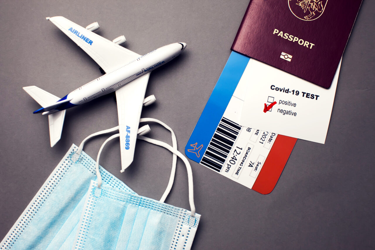 A passport and a mask on the desk metaphorically represent the future of tourism.
