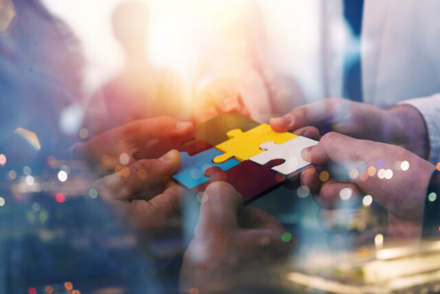 A photo shows people holding pieces of puzzles to bring humanity and technology together.