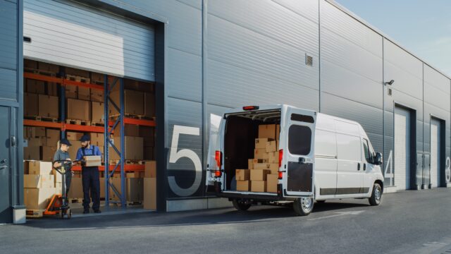 outside of a storehouse with a truck next to it filled with boxes
