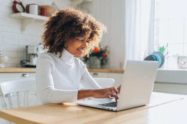Dark skinned girl looks in laptop and enjoys online shopping