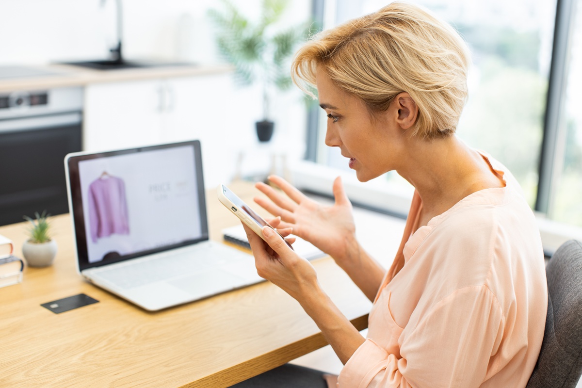 Frustrated woman on the phone, talking about different prices when shopping online.