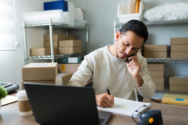 Small business owner talking with clients, while looking at laptop.