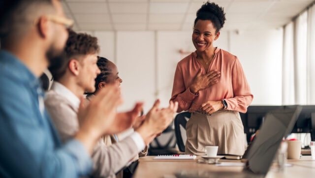 A group of colleagues applauding a smiling colleague, symbolizing employee recognition programmes